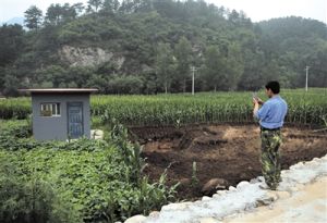 被糞水污染的地里種植的玉米已被挖土機挖掉。該片土地旁的小房內則是該村水源的水井。