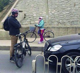 一名老外把腳踏車橫在腳踏車道，阻止一輛違章車輛通過。