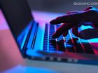 silhouette of male hand typing on laptop keyboard at night