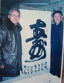 　1999年8月5日，在武昌青少年書畫展覽大廳，為全國著名書法評論家陳方既先生（右）書榜書《壽》字紀念。何勛（左）