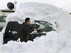 （圖）日本婦女清理自家汽車上的積雪