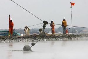 印尼工作人員將使用鉸鏈連線在一起的混凝土球沉入泥漿