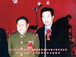 2002年在中國革命軍事博物館海內外書畫大展中獲金獎，中國書協副主席李鐸頒獎併合影留念