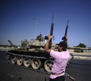 2011年8月21日，一名利比亞反對派武裝人員在利比亞首都的黎波里西部地區舉起手中的武器。
